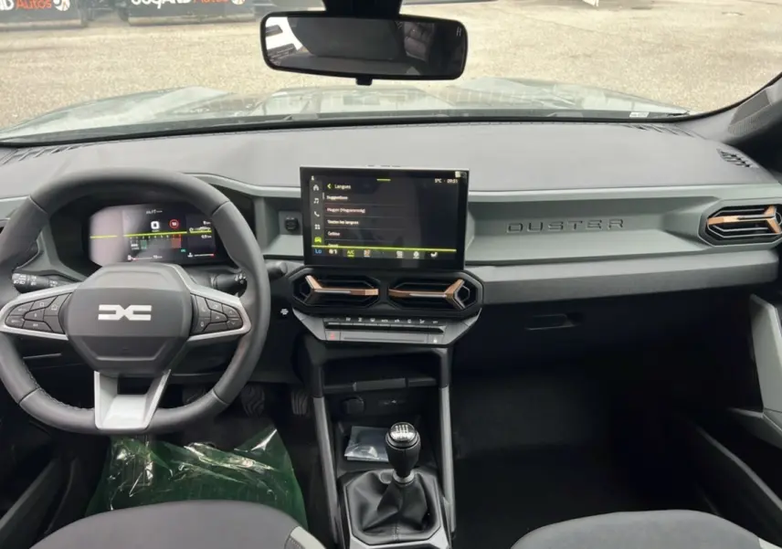 Vue intérieure du tableau de bord du Dacia Duster 2025 kaki lichen, avec volant multifonction et écran tactile central.