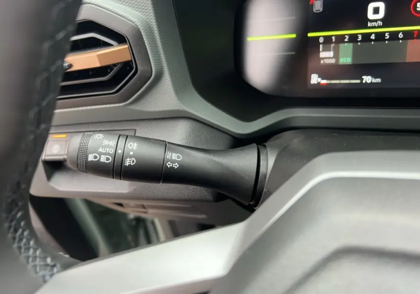 Gros plan sur la commande des phares à gauche du volant dans le tableau de bord du Dacia Duster 2025 kaki lichen.