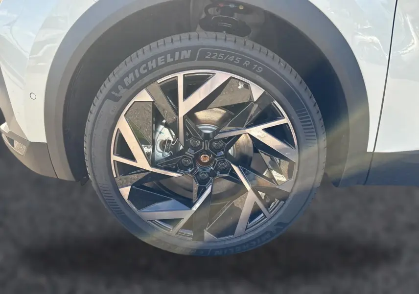 Gros plan sur la roue avant droite d’une Renault Symbioz blanc nacré avec jante alu noire et argentée au design géométrique.