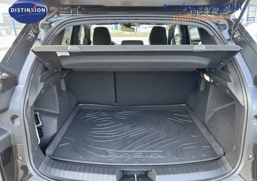 Coffre ouvert d'un Dacia Duster noir métal 2024, mettant en valeur le tapis de coffre avec logo DACIA.