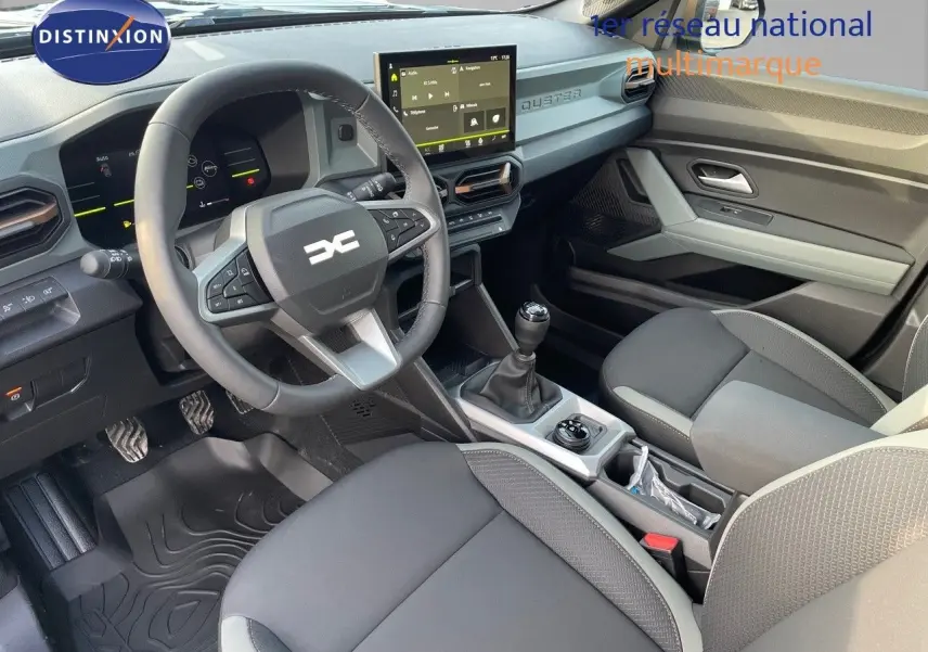 Intérieur du Dacia Duster 2024 noir métal, vue côté conducteur montrant volant, tableau de bord digital et levier de vitesse manuel.