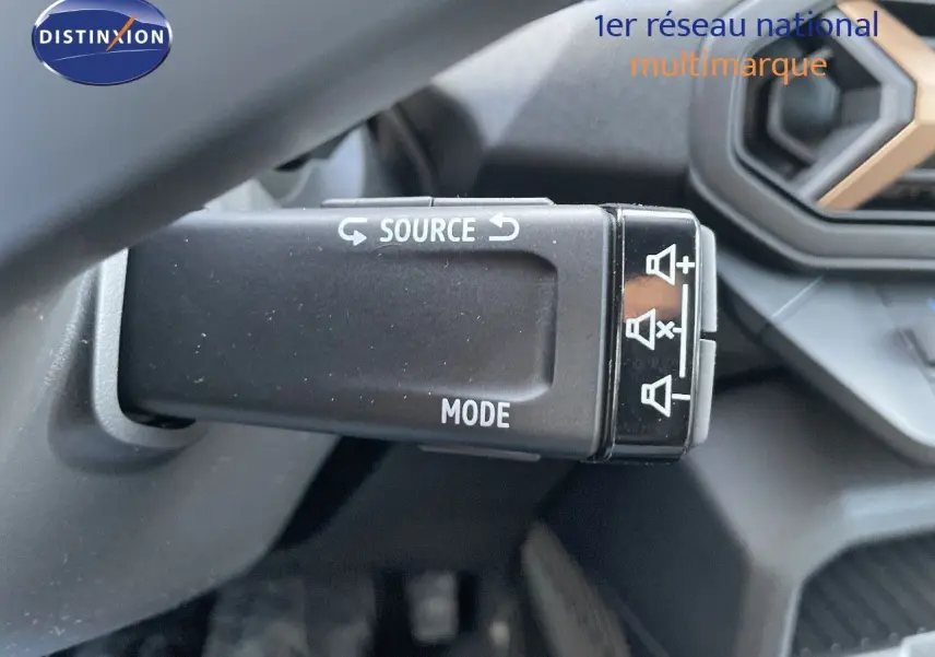 Gros plan sur la commande multimédia au volant du Dacia Duster noir métal 2024, avec détails des boutons source et mode.