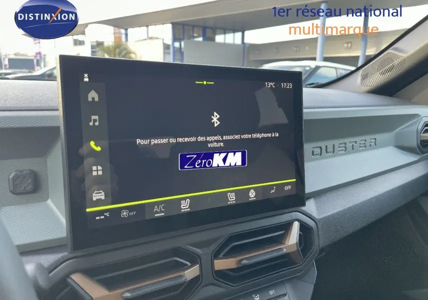 Vue intérieure du tableau de bord du Dacia Duster 2024 avec écran tactile et inscription DUSTER sur la planche de bord.