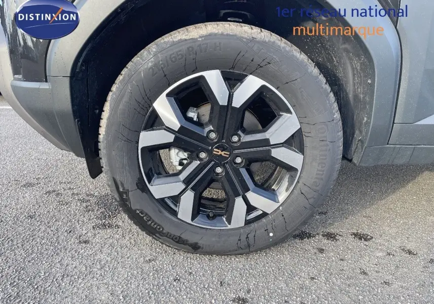 Gros plan sur la roue avant gauche du Dacia Duster noir métal 2024, mettant en valeur la jante bi-ton distinctive.