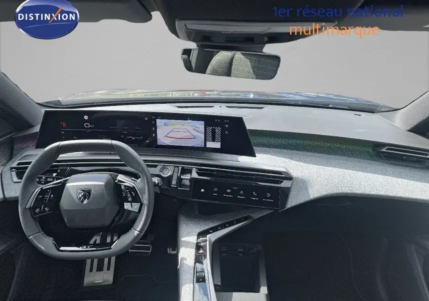 Vue intérieure du tableau de bord et volant du Peugeot 5008 Hybrid GT 2025 en noir perle métal, avec écran central et caméra de recul affichée.