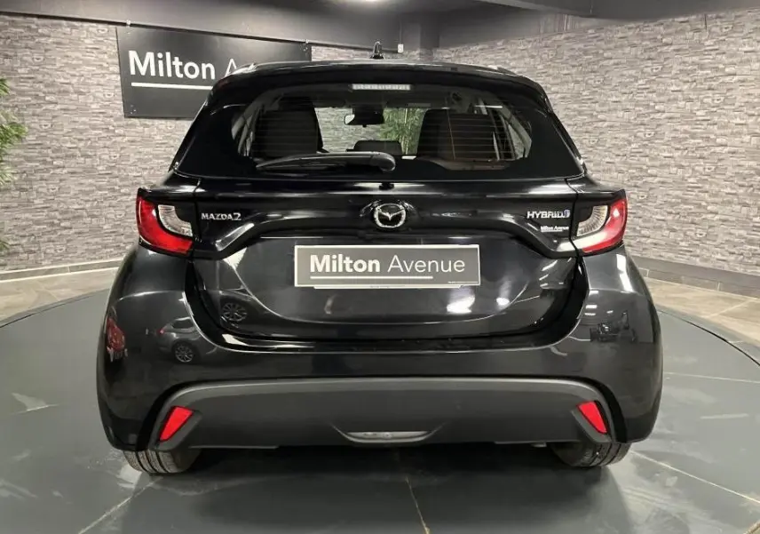 Vue arrière d'une Mazda2 noire hybride 2023 avec feux arrière LED et logo Mazda bien visibles.