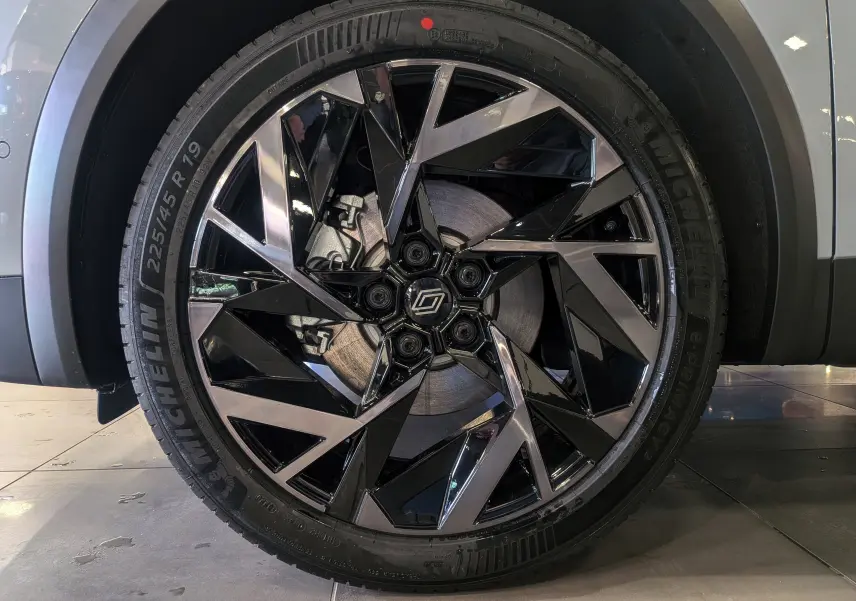 Gros plan sur la jante noire et argentée au design géométrique du Renault Symbioz gris Rafale, roue avant droite visible.