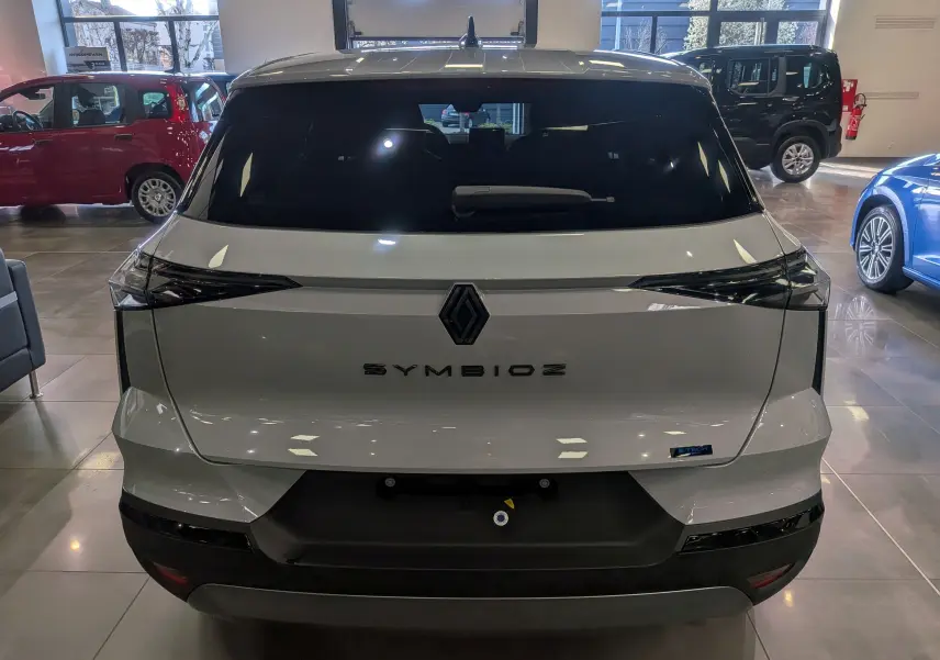 Vue arrière d’un Renault Symbioz gris Rafale en showroom, avec logo central et feux arrière noirs étirés.