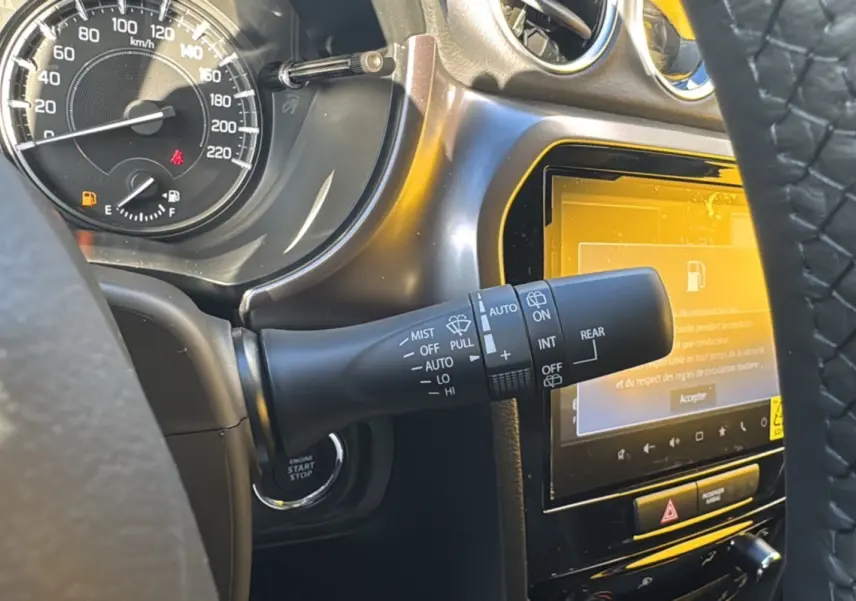 Gros plan sur la commande d’essuie-glace et le tableau de bord noir du Suzuki Vitara Hybrid 2025, écran tactile allumé.