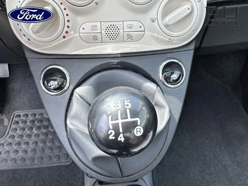 Le levier de vitesses manuel noir de la FIAT 500 Lounge 2018 vu de dessus, entouré de commandes de climatisation.