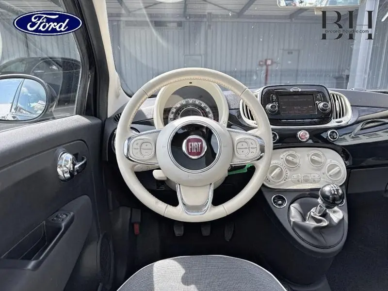 Vue intérieure avant centrée sur le volant beige et tableau de bord blanc de la Fiat 500 Crossover Black Métal 2018.