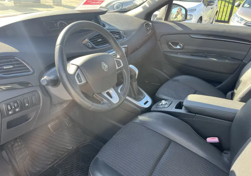 Vue intérieure côté conducteur du Renault Scenic III noir de 2012, volant cuir et console centrale avec boîte automatique.