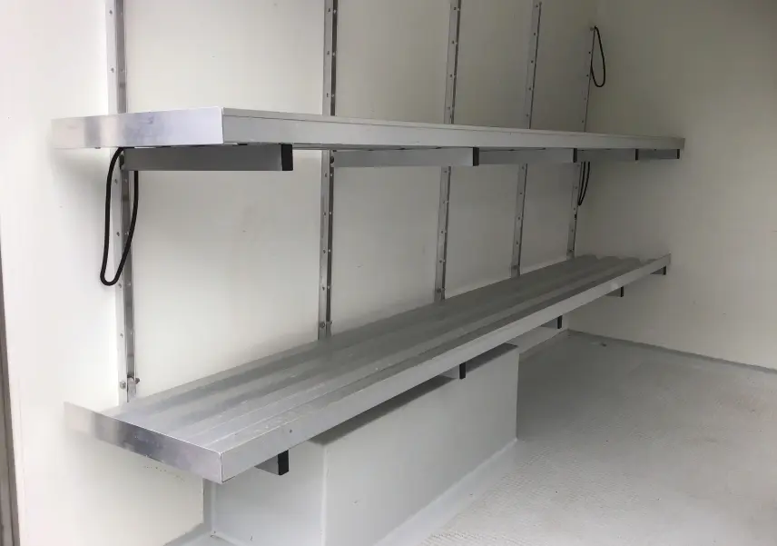 Intérieur de la caisse frigorifique blanche du Renault Trafic Planche cabine, montrant les étagères métalliques sur le côté gauche.