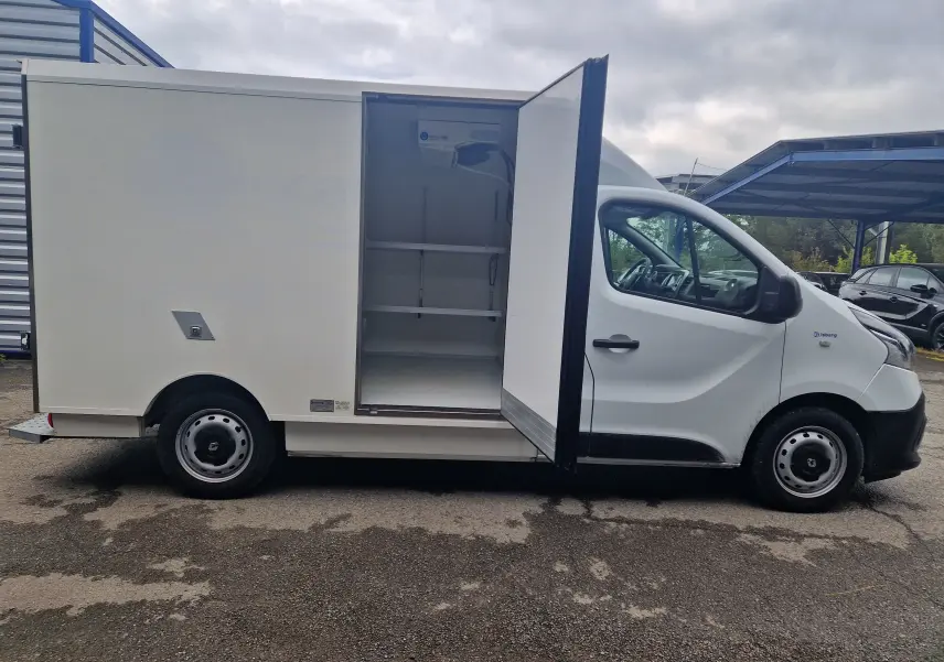 Vue latérale droite d'un Renault Trafic plancher cabine blanc 2019 avec porte latérale ouverte montrant la caisse frigorifique ICEBERG équipée d'étagères.
