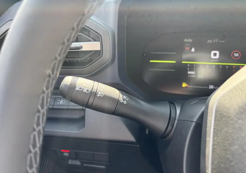 Gros plan sur la manette des feux et clignotants à gauche du volant dans le tableau de bord digital du Dacia Duster 2025.