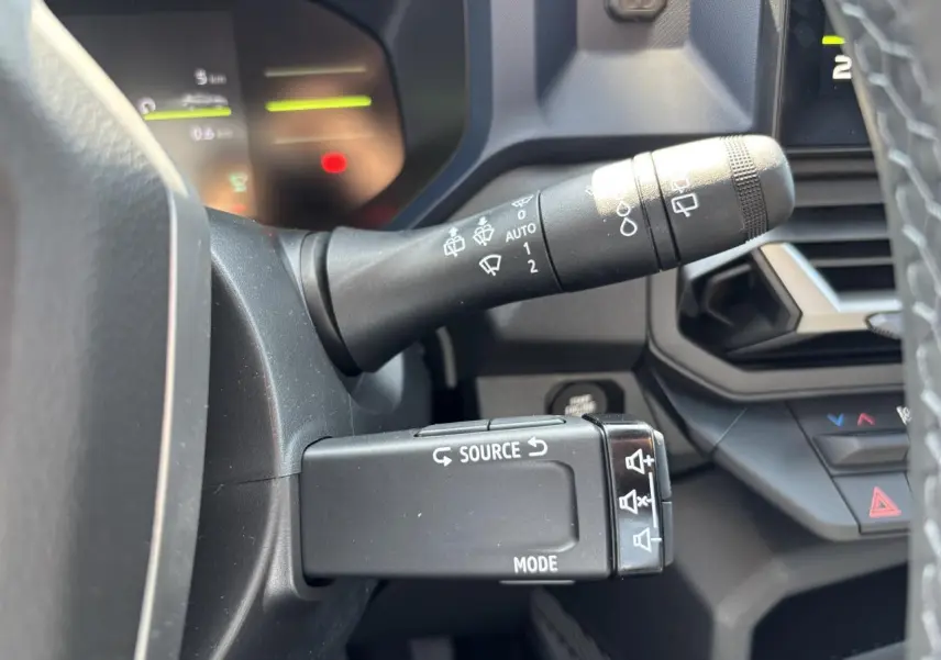 Gros plan sur les commandes au volant du Dacia Duster 2025, avec tableau de bord digital en arrière-plan.