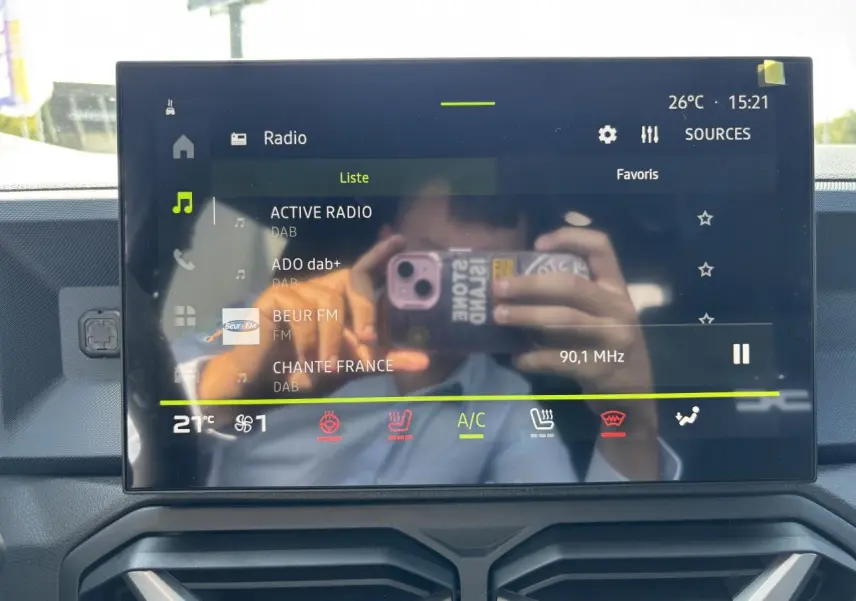 Écran tactile central du Dacia Duster 2025 affichant la radio numérique et commandes climatisation, intérieur moderne.