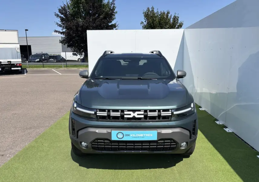 Vue de face du Dacia Duster 2025 en vert cèdre métallisé avec calandre moderne et feux LED fins.