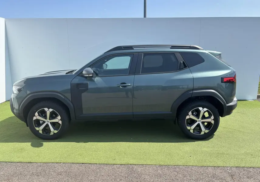 Profil côté gauche du Dacia Duster 2025 vert cèdre métallisé avec jantes alliage 18 pouces diamantées.