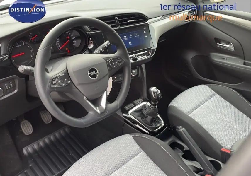 Vue intérieure avant droite de l'Opel Corsa 2025, montrant le volant multifonction, la boîte manuelle et les sièges gris clair.