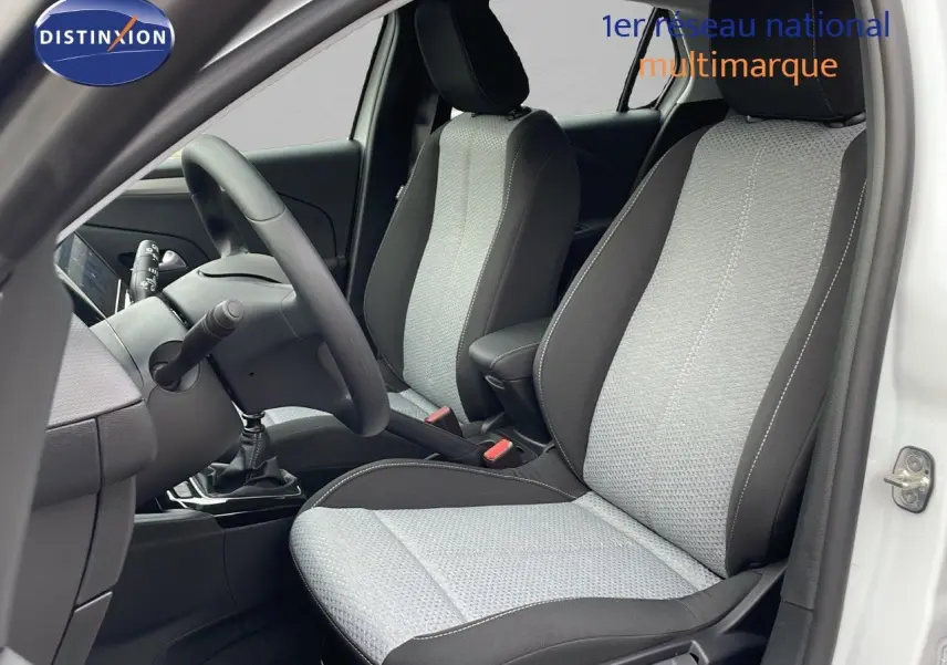 Vue intérieure côté conducteur de l'Opel Corsa blanc arctique 2025 avec sièges tissu bicolore gris et noir.