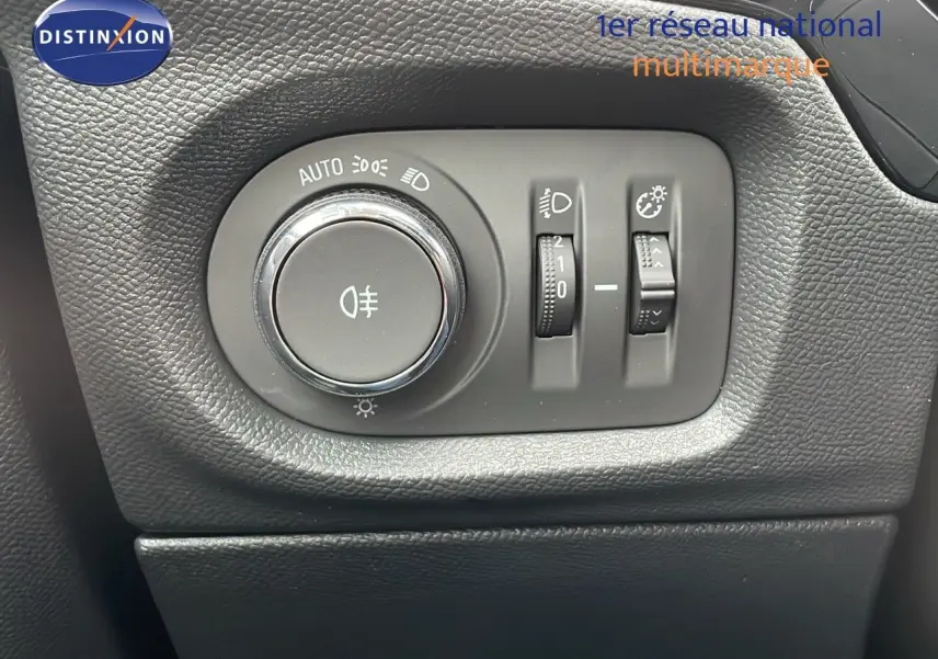 Gros plan sur les commandes d'éclairage noires à gauche du tableau de bord d'une Opel Corsa blanche Arctic 2025.