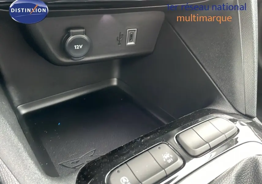 Gros plan sur la console centrale de l'Opel Corsa blanc arctique, montrant prise 12V, port USB et boutons de commande.