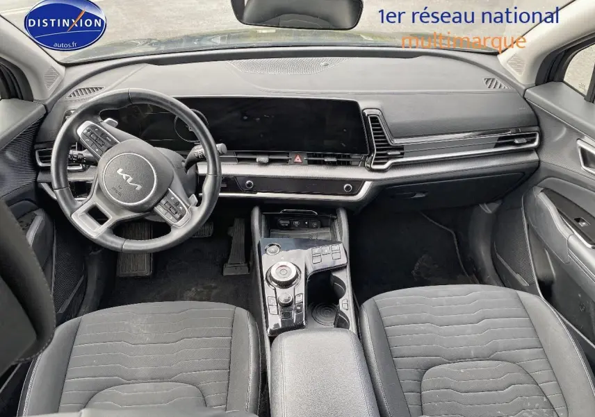 Intérieur noir du Kia Sportage 2023 vu de face, avec volant cuir multifonction et large écran tactile.