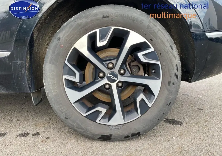 Gros plan sur la roue avant droite du Kia Sportage noir 2023 avec jante alu au design moderne.