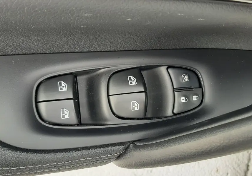 Gros plan sur les commandes des vitres électriques et verrouillage sur la porte côté conducteur d'un Nissan Qashqai blanc 2020.