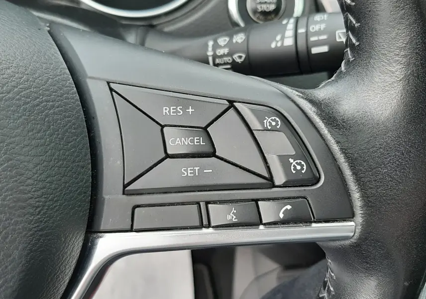 Gros plan sur les commandes au volant droit du Nissan Qashqai blanc 2020, avec boutons de régulateur de vitesse et téléphone.