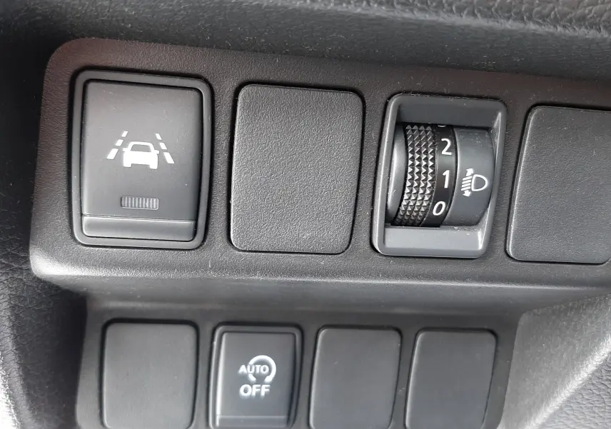 Gros plan sur les commandes de régulation d'éclairage et d'assistance au maintien de voie du Nissan Qashqai blanc 2020.