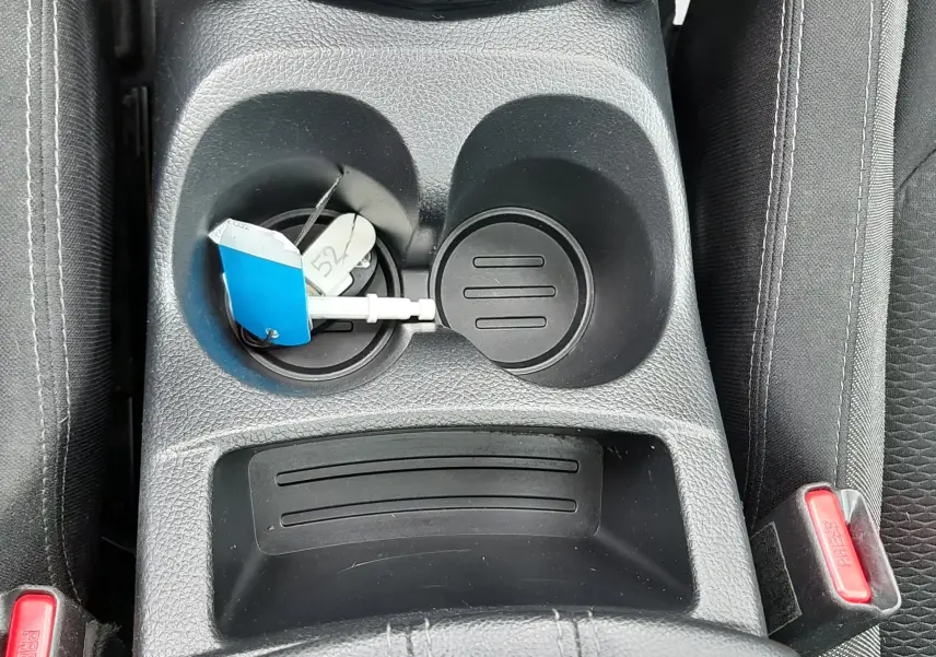 Vue rapprochée de la console centrale noire du Nissan Qashqai 2020 avec porte-gobelets et clé USB connectée.