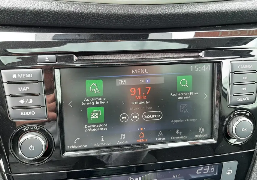 Détail de la console centrale du Nissan Qashqai blanc 2020, écran tactile affichant la radio FM et commandes climatisation.