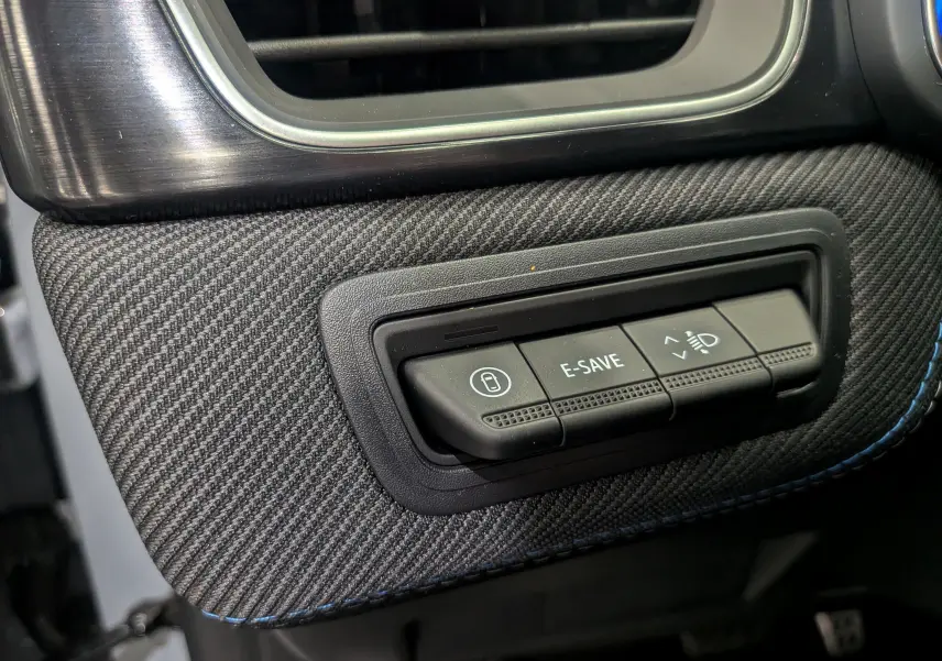 Détail intérieur du tableau de bord gris avec boutons de contrôle E-SAVE et réglage des phares sur Renault Symbioz E-TECH.