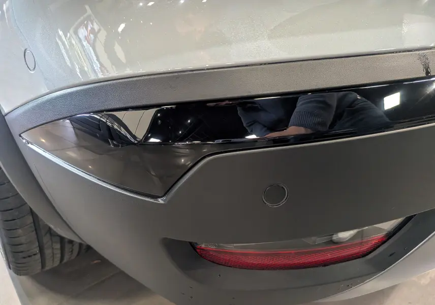 Détail du pare-chocs arrière gris Rafale du Renault Symbioz E-TECH avec insert noir brillant et feu rouge intégré.