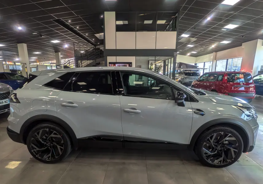 Vue de profil côté gauche d’un Renault SYMBIOZ gris Rafale en hybride essence, avec jantes noires et toit contrasté en showroom.