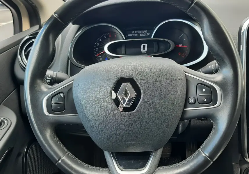 Vue intérieure centrée sur le volant noir de la Renault Clio IV Estate, avec tableau de bord et compteurs visibles.