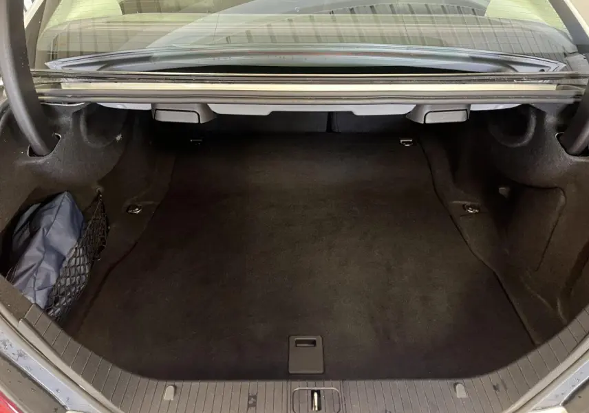 Coffre ouvert vu de l'arrière d'une Mercedes Classe CLS 350 d gris, avec filet de rangement latéral.