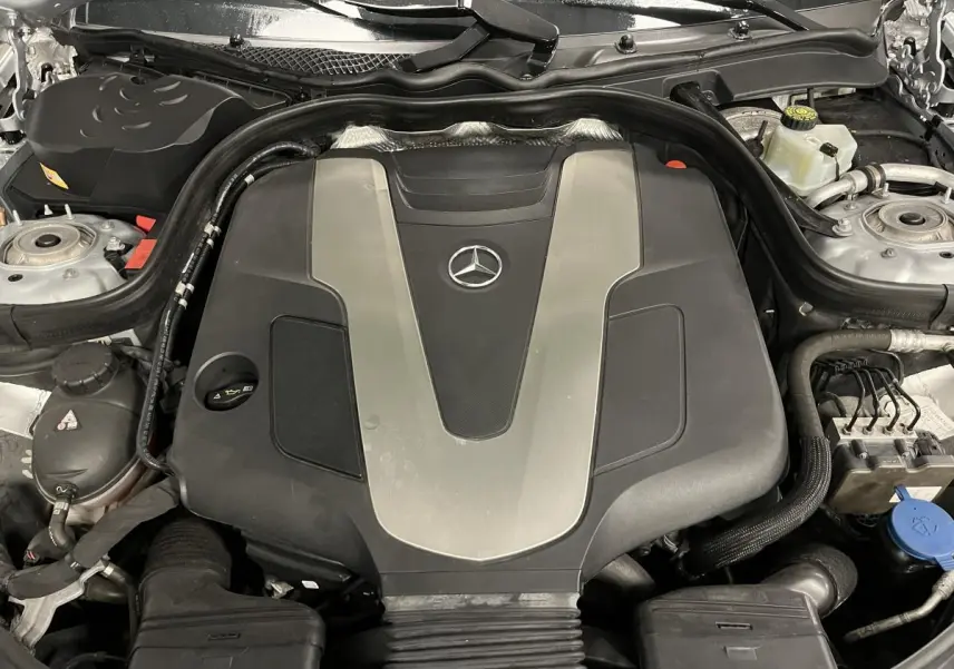 Vue rapprochée du moteur Mercedes Classe CLS 350 d 2015 avec cache noir et argenté sous le capot ouvert.