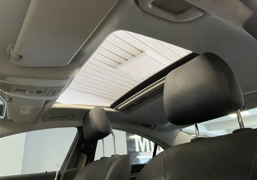 Vue intérieure montrant les appuie-têtes en cuir noir et le toit ouvrant vitré électrique d'une Mercedes CLS 350 d gris.