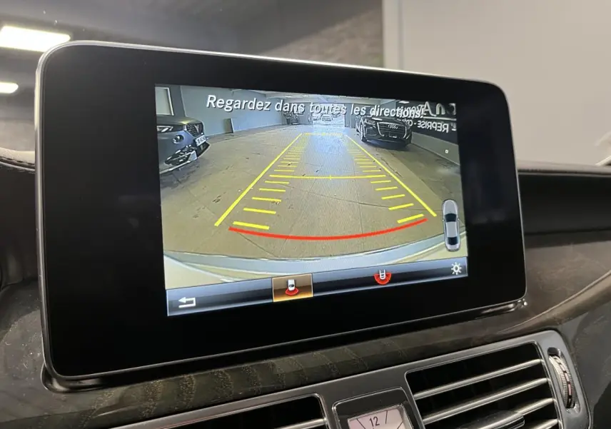 Écran central de la Mercedes CLS 350 d 2015 montrant la caméra de recul avec lignes de guidage en intérieur.