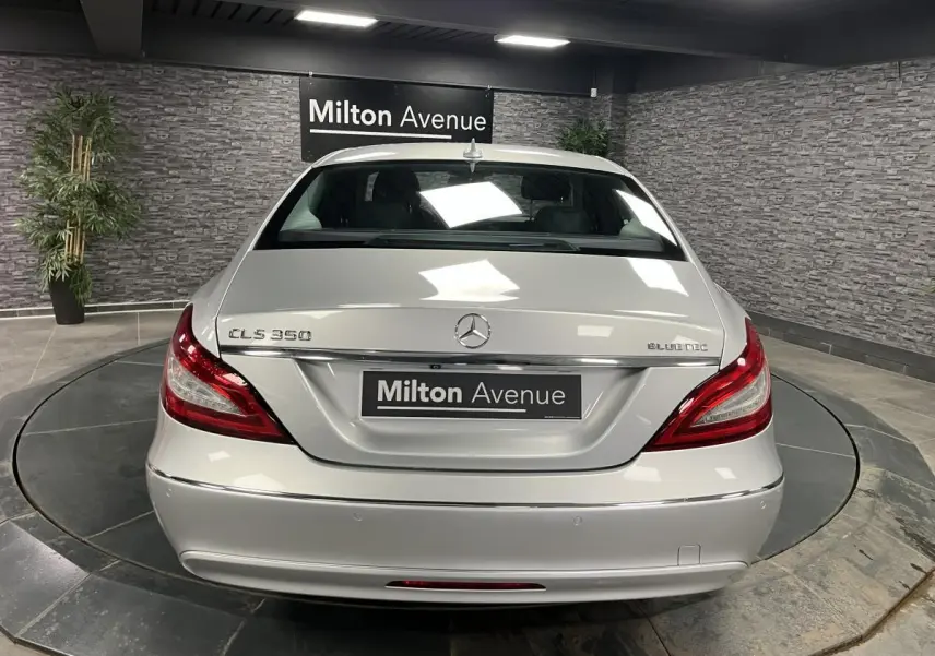 Vue arrière d'une Mercedes CLS 350 d gris clair avec feux arrière LED et logo Bluetec visible.