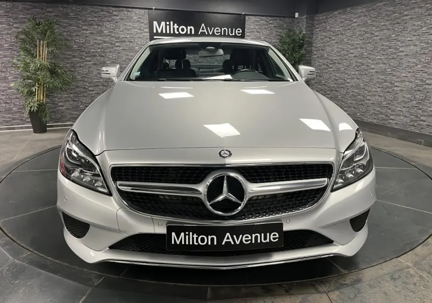 Vue frontale d'une Mercedes Classe CLS 350 d gris métallisé avec calandre chromée et logo central sur fond noir.