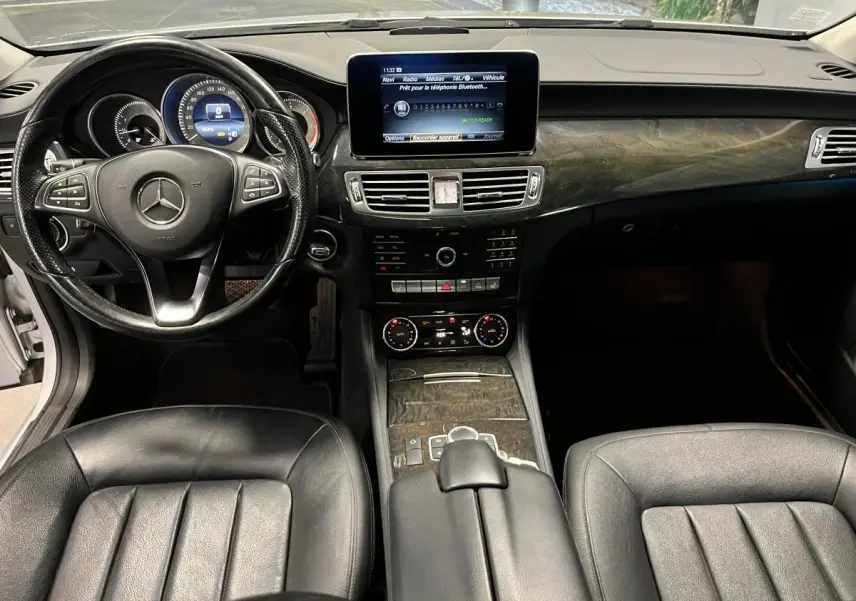 Intérieur noir cuir de la Mercedes CLS 350 d 2015, tableau de bord avec écran central et inserts bois foncé.