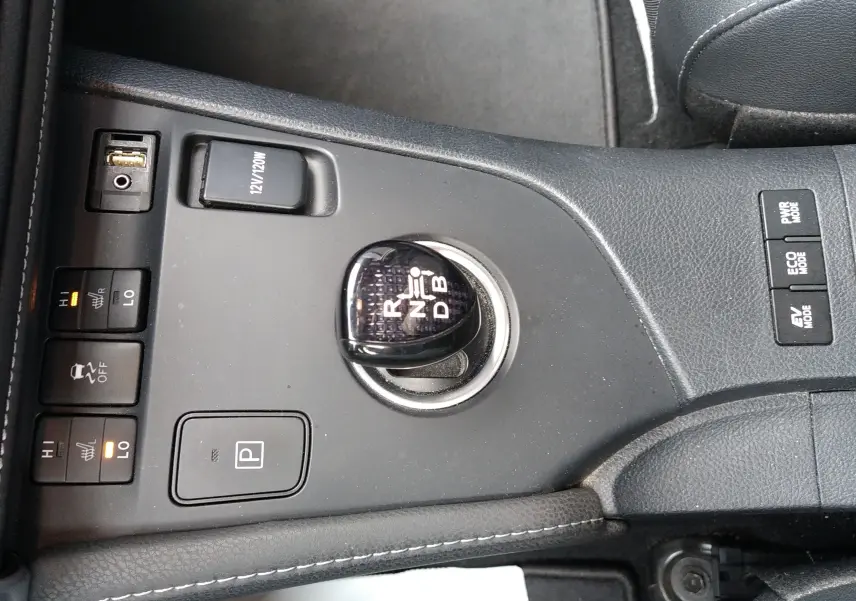 Vue rapprochée de la console centrale noire d’une Toyota Auris hybride 2016, avec levier de vitesses et commandes chauffantes.