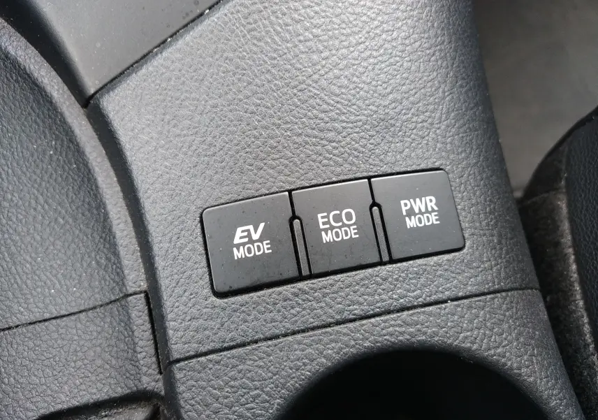 Gros plan sur les boutons EV, ECO et PWR mode sur la console centrale d'une Toyota Auris hybride blanche de 2016.