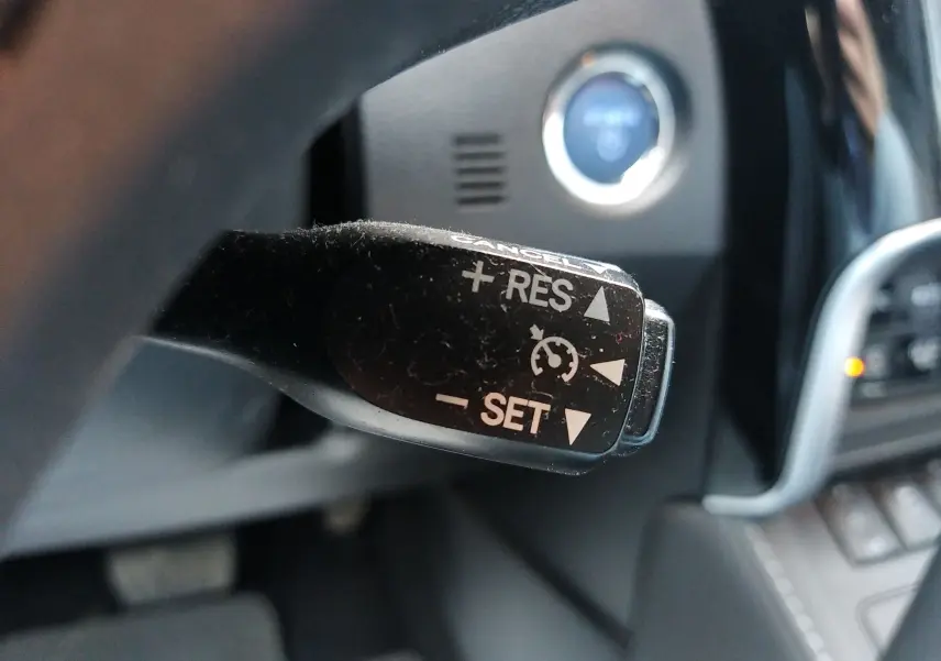 Le levier de régulateur de vitesse noir en gros plan dans l'habitacle d'une Toyota Auris blanche hybride de 2016.