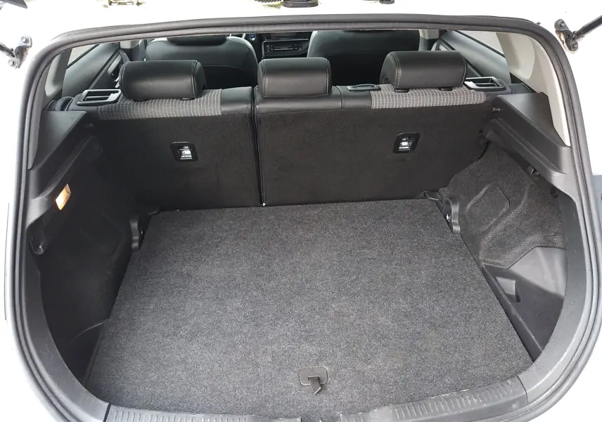 Coffre ouvert d'une Toyota Auris blanche, vue arrière montrant l'espace de chargement et les dossiers de sièges noirs.