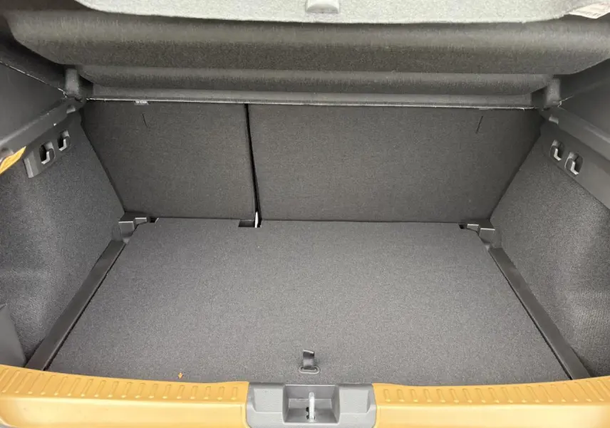 Coffre ouvert de la Dacia Sandero Stepway 2025 Beige Safari, montrant le plancher plat et les finitions intérieures grises.